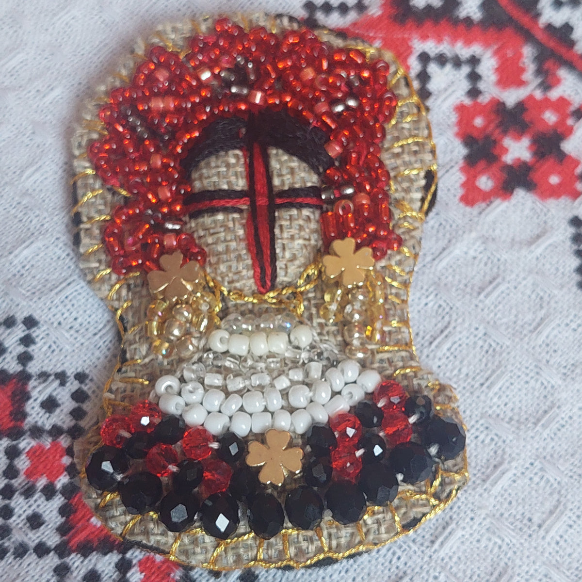 Close-up of handmade beaded Ukrainian Motanka textile brooch with decorative crystals