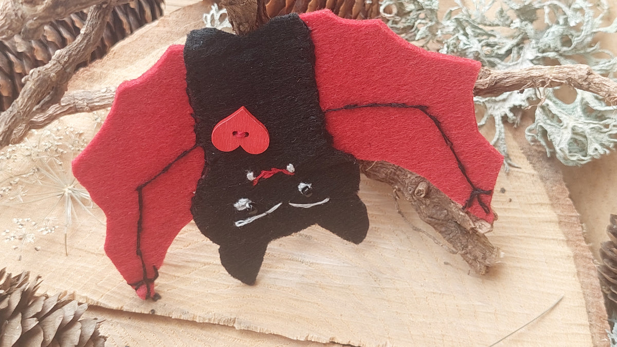 lose-up of hand-embroidered vampire bat felt brooch with beads and wooden details