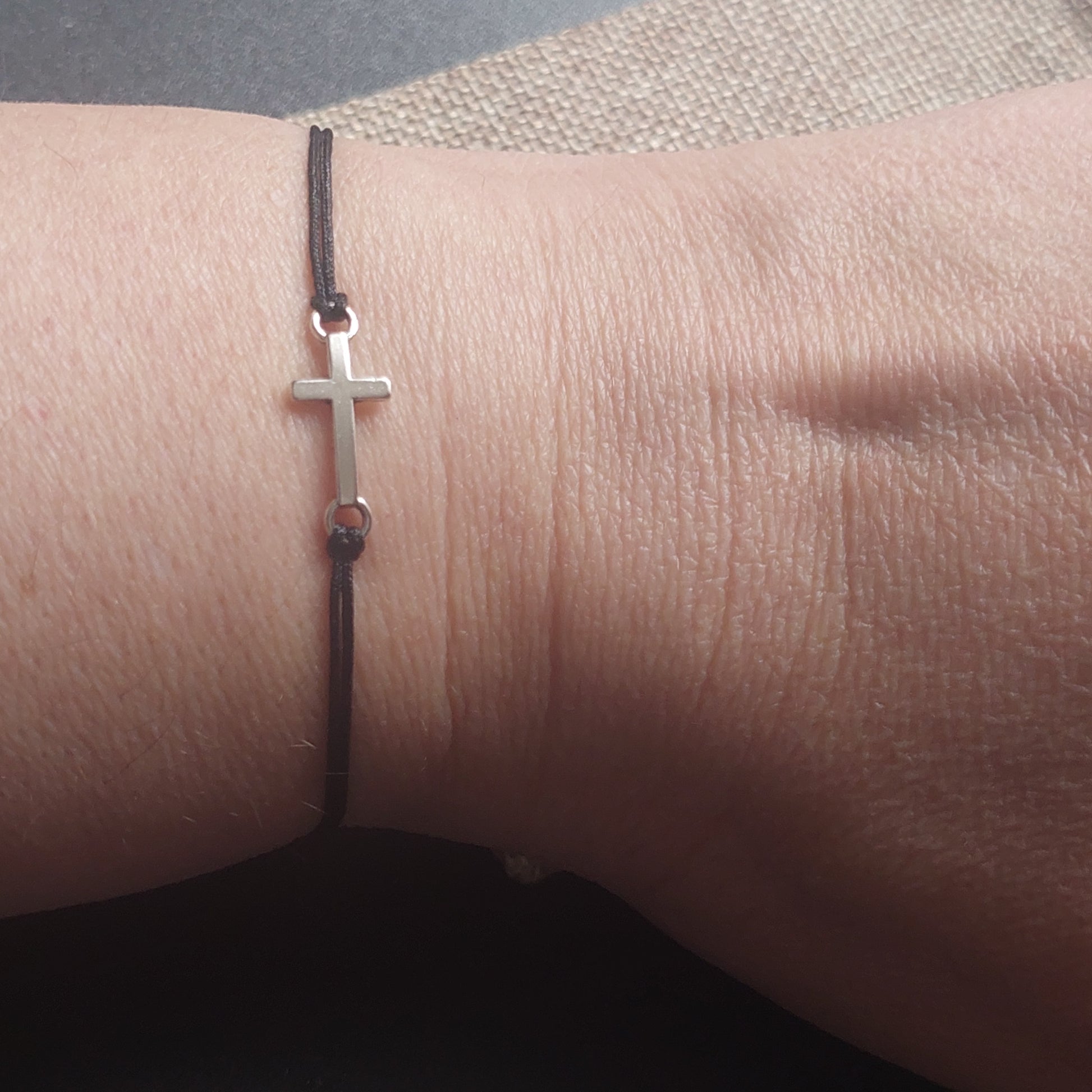 Black cross bracelet worn on wrist – gothic spiritual jewelry handmade by Angelenade