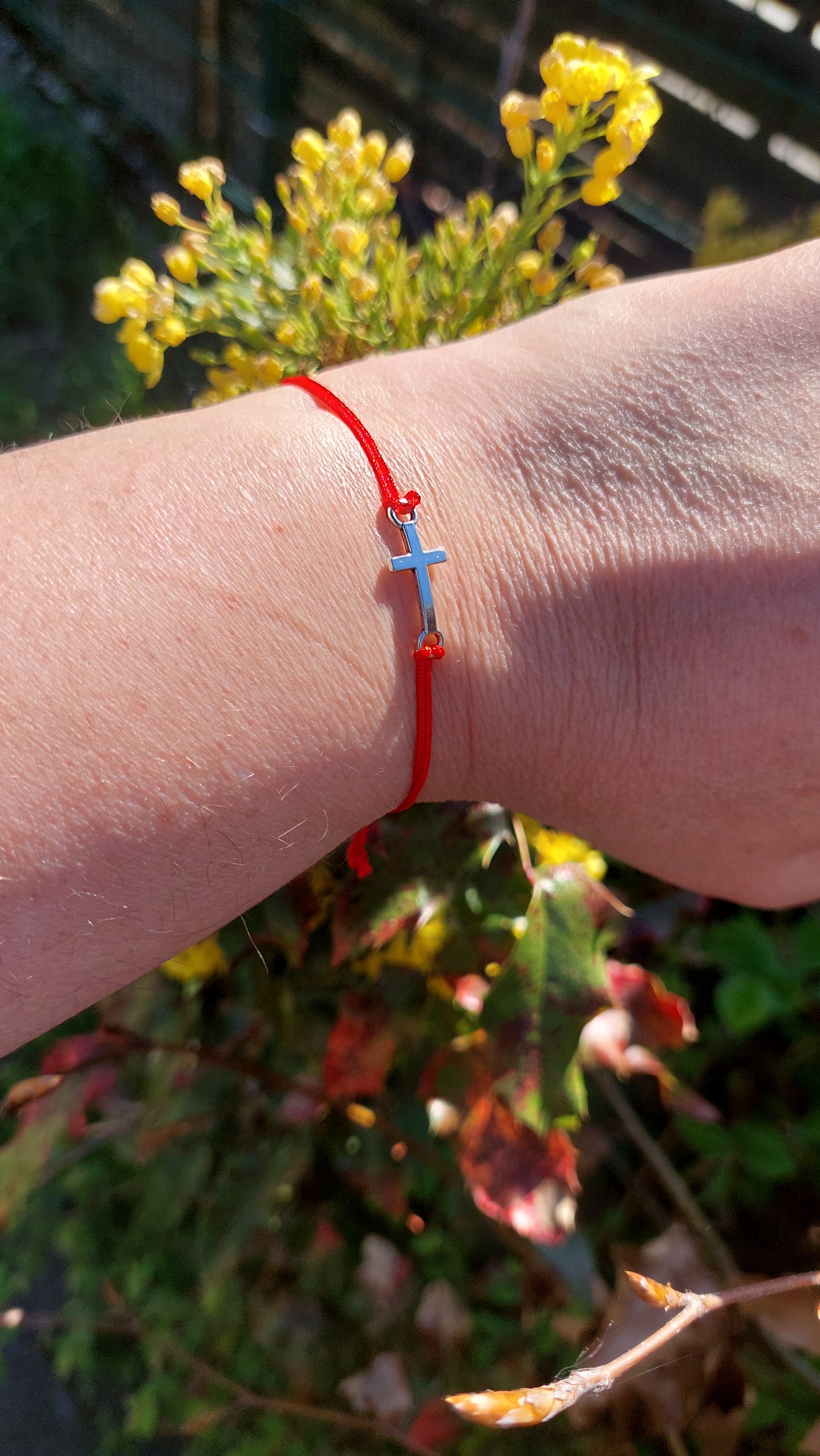 Red macrame cross bracelet worn on wrist – handmade by Angelenade