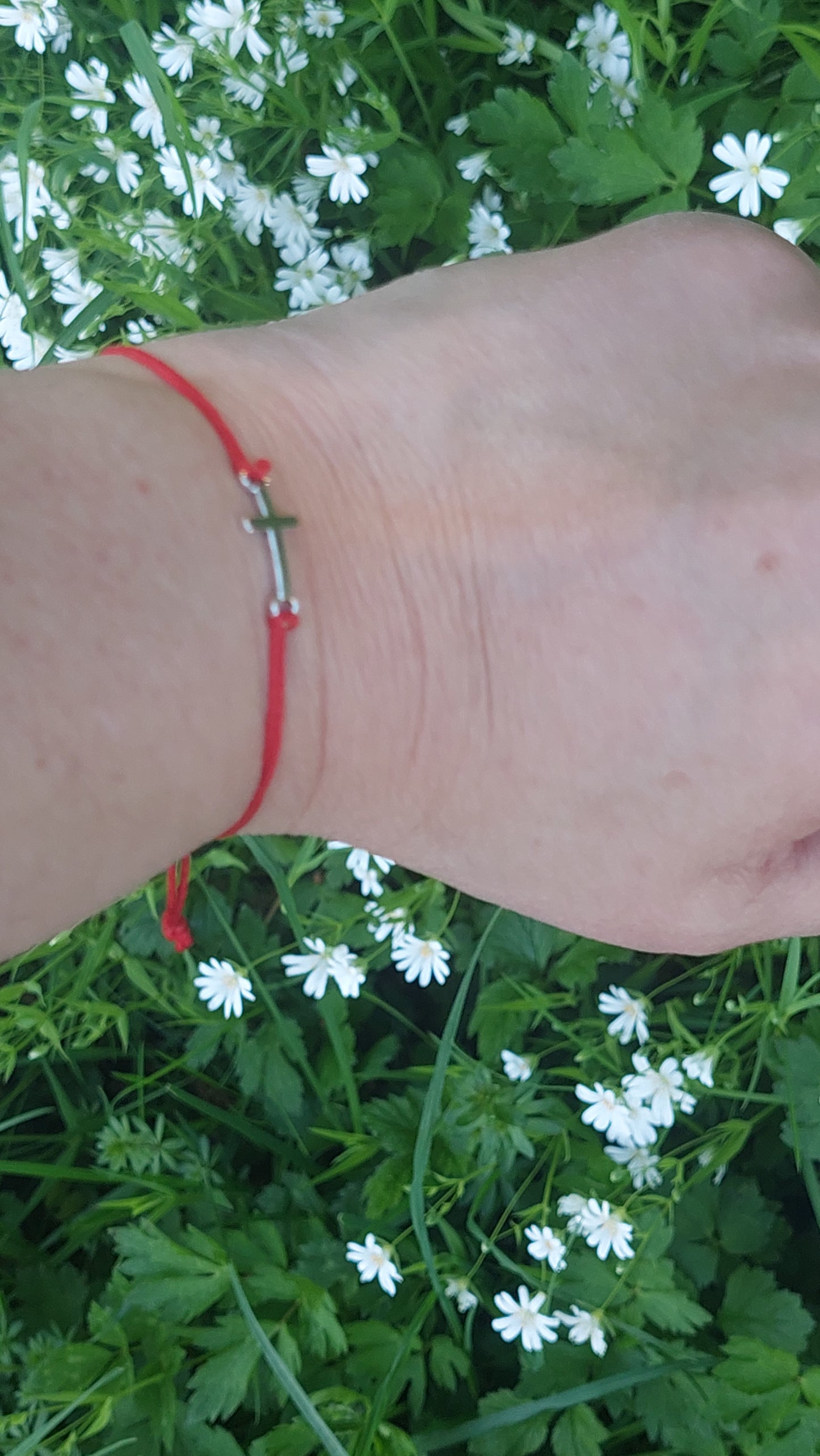 Red macrame cross bracelet worn on wrist – gothic spiritual jewelry handmade by Angelenade